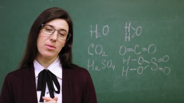 Educación en línea. La profesora está impartiendo clases de química en línea en la escuela. fondo de pizarra con fórmulas escritas en él. enseñanza remota. streaming de vídeo en directo desde clase. — Vídeo de stock