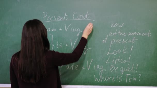 Enseignement en ligne. professeur explique le matériel pendant la leçon d'anglais en ligne. Elle écrit des règles de grammaire avec de la craie sur le tableau noir, en classe. enseignement à distance. streaming vidéo en direct depuis la classe. — Video