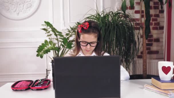 Fernunterricht, Online-Schulung. Schulmädchen schaut sich Online-Tutorial-Video-Lektion auf Laptop und Notizen in Copybook. Online lernen zu Hause. — Stockvideo