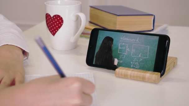 Educación a distancia, educación en línea. primer plano de la pantalla del teléfono inteligente. colegiala viendo en línea tutorial lección de vídeo y tomar notas en copybook. estudiar en línea en casa. — Vídeos de Stock