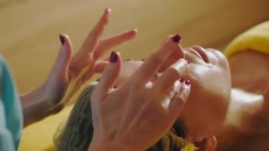 Yaşlanma önleyici prosedür, yüz masajı. Yakın plan. Kadın kanepede uzanıyor ve yüz masajı yaptırıyor. Güzellik kliniğinde yüz ve yüz derisi kanalizasyonu için. Cilt bakımı, kozmetoloji