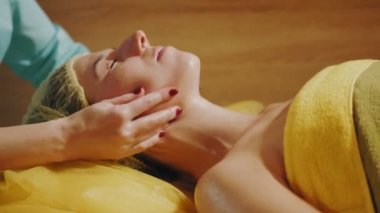 Yaşlanma karşıtı kozmetoloji. Yüz masajı. Yakın plan. Kadın kanepede uzanıyor ve yüz masajı yaptırıyor. Güzellik kliniğinde yüz ve yüz derisi kanalizasyonu için. Cilt bakımı, kozmetik