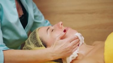 Kozmetoloji, yüz temizleme. Kadınlar için kozmetik prosedürler. Yakın plan. Kadın kanepede uzanıyor ve güzellik kliniğinde yüz temizleme ameliyatı oluyor. Cilt bakımı, cilt bakımı.