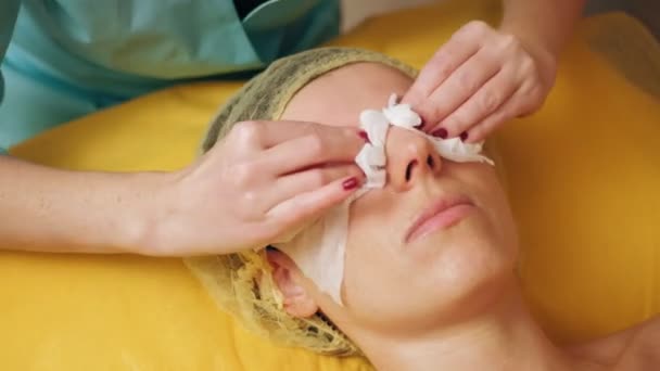 Cosmetologia, pulizia del viso. procedure cosmetiche per le donne. primo piano. donna è sdraiata sul divano e ottenere la procedura di compensazione del viso, presso la clinica di bellezza. Cura della pelle, trattamento dermatologico. — Video Stock