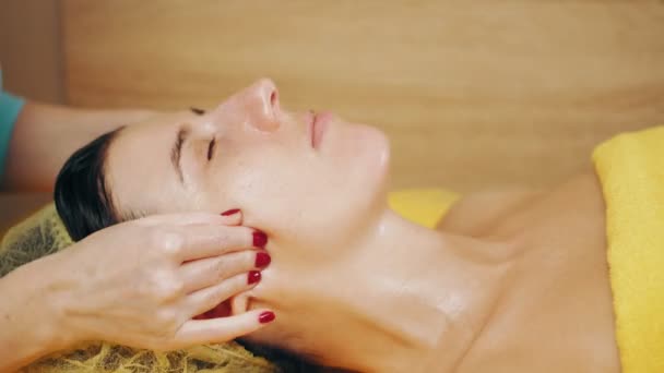 Cosmetología, masaje facial. Primer plano. mujer está acostada en el sofá y recibiendo masaje facial, músculos tonificados y drenaje linfático de la piel facial, en la clínica de belleza. Cuidado de la piel, procedimiento antienvejecimiento — Vídeos de Stock