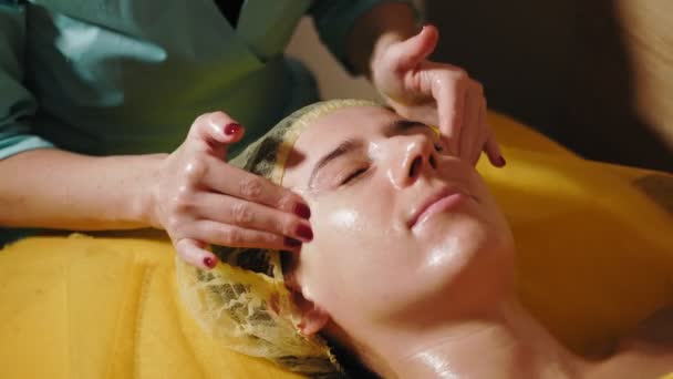 Procedimiento anti-envejecimiento, masaje facial. Primer plano. mujer está acostada en el sofá y recibiendo masaje facial para tonificar los músculos y el drenaje linfático de la piel facial, en la clínica de belleza. Cuidado de la piel, cosmetología — Vídeos de Stock