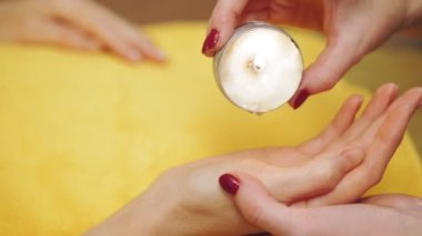 Kozmetoloji, el bakımı prosedürü. El masajı. Parafin terapisi. Güzellik uzmanı kibarca uygular ve bir kadının eline parafin sürer. .