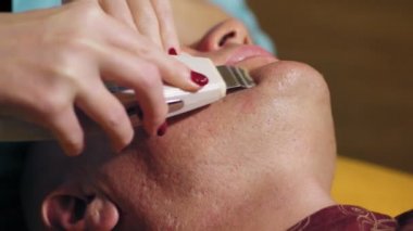 Kozmetoloji, erkeklerin yüz temizliği. Erkekler için kozmetik prosedürler. Adam kanepede uzanıyor ve ultrasonik kabartma yaptırıyor, yüz temizleme prosedürü, güzellik kliniğinde. Cilt bakımı dermatoloji tedavisi.