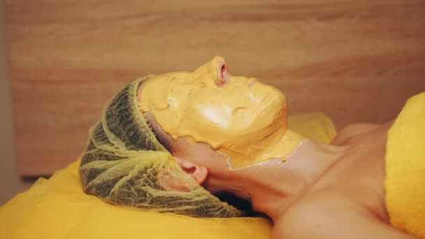 Cosmetología, procedimientos de cuidado facial de la piel. Primer plano. procedimiento de usar una máscara cosmética de alginato dorado en una cara de mujer. cosméticos antienvejecimiento. — Vídeos de Stock