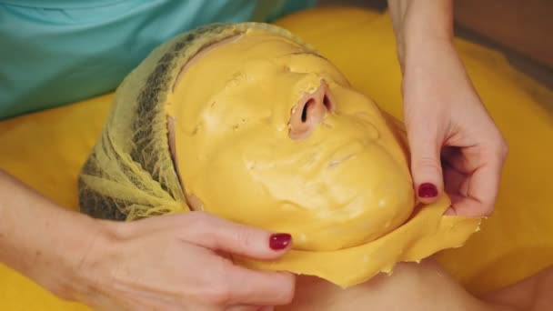 Kosmetika, ošetření pleti. detailní záběr. kosmetička pečlivě odstraňuje zamrzlou alginátovou masku z obličeje žen. anti-aging kosmetika. — Stock video