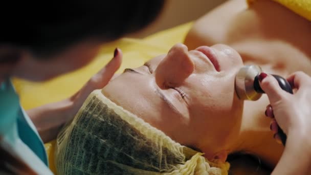 Cosmetologie, gezichtsverzorging. close-up. fonoforese procedure voor gezichtshuid. schoonheidsspecialiste leidt speciale manipulatie langs massage lijnen op het gezicht. cosmetica tegen veroudering. — Stockvideo