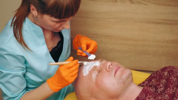 Cosmetología, procedimientos cosméticos para hombres. el hombre está acostado en el sofá y recibiendo el procedimiento de cuidado facial de la piel, en la clínica de belleza. Cuidado de la piel, tratamiento dermatológico. — Vídeo de stock