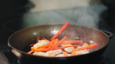 Yemek pişirmek. Yakın plan. Sebzeli et parçaları tavada kızartılır. Aşçılık