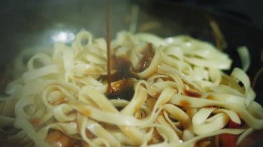 Makarna. Yakın plan. Sebzeli makarna tavada kızartılır. Makarnanın üzerine farklı soslar dökülüyor. Aşçılık. Mutfakta yemek hazırlama süreci, mutfak....