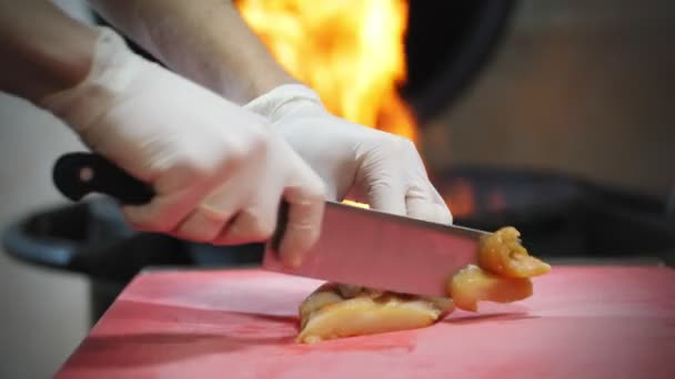 Кулінарія. шеф-кухар, в захисних рукавичках, нарізає м'ясо, куряче філе, нарізає м'ясо на шматки. крупним планом перегляд . — стокове відео