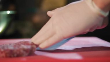 Aşçılık. Hamburger pişirmek. Yakın plan. Tek kullanımlık eldiven giyen şef kıymalı köfte yapıyor. Aşçı hamburger için sığır eti madalyonu yapar. Fast food, abur cubur.