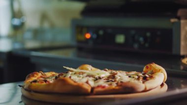 Aşçılık. Pizza yapmak. Yakın plan. Şef yeni hazırlanmış, üzerine salata yaprakları ve bitkiler serpiştirilmiş sıcak pizza serpiştiriyor. İtalyan pizzası pişirme süreci .