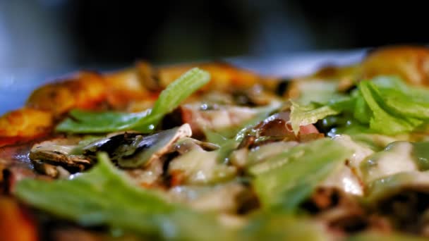 La cuisine. faire de la pizza. Gros plan. Délicieuse, juteuse, fraîchement préparée, pizza chaude avec des feuilles de laitue, des herbes, sur le dessus. processus de cuisson de la pizza italienne . — Video