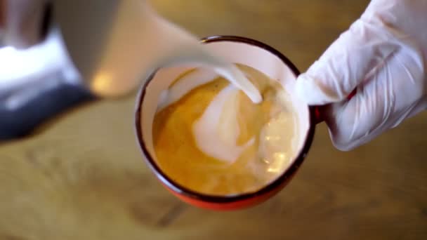 Cervejaria de café profissional. Close-up. xícara de café arte latte. barista está fazendo café arte latte com leite, desenha um padrão de leite na espuma de café. — Vídeo de Stock