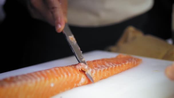 伝統的な和食。寿司の準備。接近中だ。寿司職人は、魚の寿司を準備する前に、白いまな板の上にナイフで新鮮な鮭の切り身をスライスしています。日本料理のレシピ. — ストック動画