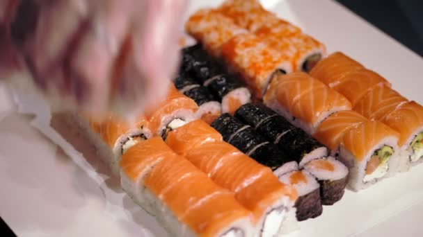 Tradycyjne japońskie jedzenie. zbliżenie. profesjonalny kucharz Sushi wkłada świeżo przygotowane bułki sushi do pudełka na wynos z baru sushi. — Wideo stockowe