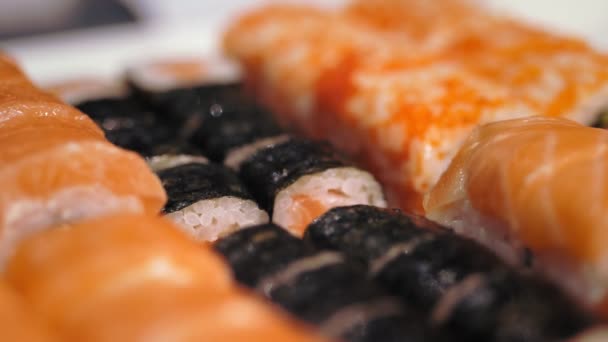 Tradycyjne japońskie jedzenie. zbliżenie. świeżo ugotowane, urozmaicone bułki sushi w pudełku na wynos z baru sushi. — Wideo stockowe