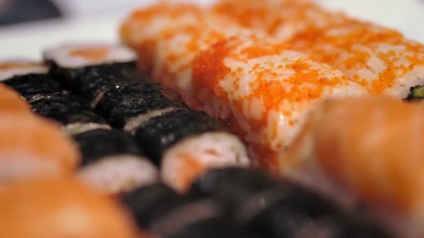 Comida tradicional japonesa. close-up. rolos de sushi acabados de cozinhar, variados em uma caixa de entrega para levar do bar de sushi. — Vídeo de Stock