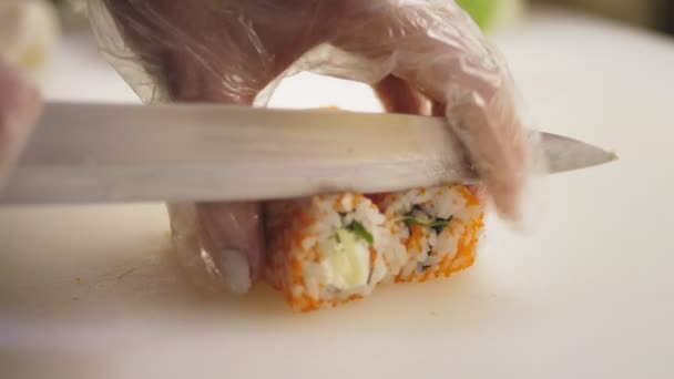 Tradycyjne japońskie jedzenie. zbliżenie. profesjonalny kucharz Sushi robi sushi rolki, kroi je na kawałki, na białej desce do krojenia, w kuchni sushi bar. — Wideo stockowe