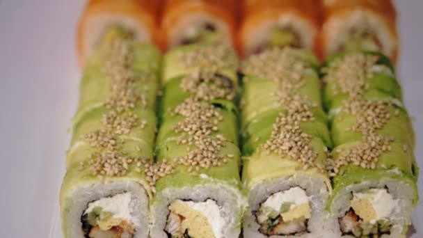 Tradiční japonské jídlo. detailní záběr. čerstvě uvařené, pestrobarevné sushi závitky v krabici na donášku ze sushi baru. — Stock video