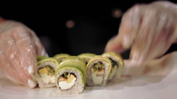 Tradycyjne japońskie jedzenie. zbliżenie. profesjonalny kucharz Sushi wkłada świeżo przygotowane bułki sushi do pudełka na wynos z baru sushi. — Wideo stockowe