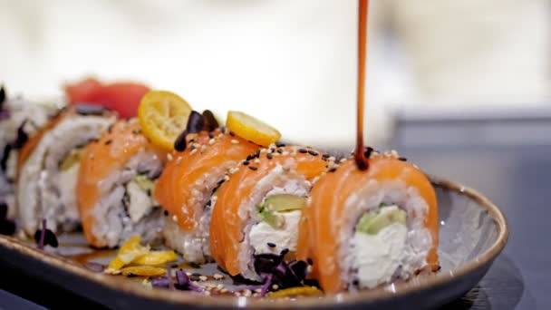 Tradycyjne japońskie jedzenie. zbliżenie. Sushi Chef zdobi sosem świeżo ugotowane bułki sushi, podawane na pięknym talerzu. sztuka służąca w restauracji. — Wideo stockowe