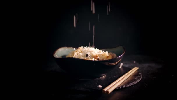 Традиционная японская кухня. крупным планом. Шеф-повар посыпает горячую лапшу с морепродуктами сыром пармезан. Замедление. искусство сервировки в ресторане — стоковое видео