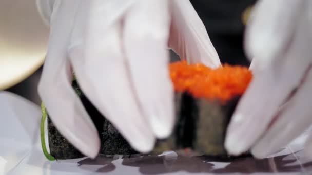 Comida tradicional japonesa. close-up. profissional Sushi Chef está colocando vários rolos de sushi recém-preparados em uma caixa de entrega para tirar do bar de sushi. — Vídeo de Stock