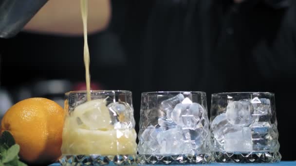 Le barman prépare des cocktails. Gros plan. le barman verse le cocktail dans les verres du shaker. au bar, restaurant ou discothèque. — Video
