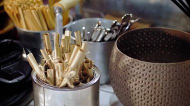 Kafe ve restoran için sofra takımı. Mutfak aletleri, çatal bıçak takımı. Yakın plan. Tahta kahve çubukları, metal çay kaşıkları, masadaki dekoratif kovalarda diğer çatal bıçak tezgahları..