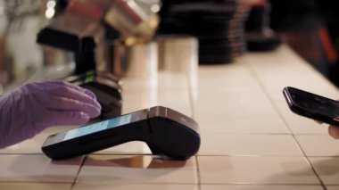 NFC teknolojisi. Yakın plan. Müşteri, restoranın bar tezgahında, terminalden ulaşılamayan ödemeler için akıllı telefon kullanıyor. Elektronik ödeme makinesinden ya da kart okuyucudan ödemeyi telefonla yapın. Cep telefonu