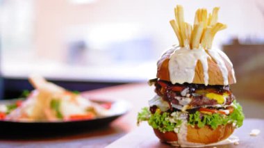 Hamburger, hamburger. Yakın plan. Tahta tepside, sulu, lezzetli, taze hazırlanmış, patates ve soslu yağlı bir burger. Fast food, abur cubur.