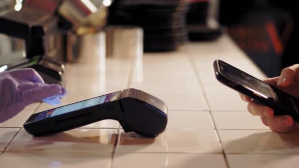 Technologie NFC. detailní záběr. zákazník používá smartphone pro bezkontaktní platbu přes terminál, na barovém pultu restaurace. Platit telefonicky na elektronickém platebním stroji nebo čtečce karet. Mobilní