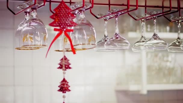 Nettoyer les verres au bar. Gros plan. différents types de verres pour boissons et cocktails accrochés sur des supports spéciaux au-dessus du bar avec décor de Noël — Video