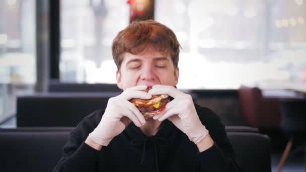 Fast food, junk food. portrait. young handsome guy eating juicy, tasty, freshly prepared, fatty burger, hamburger, with appetite. — Stock Video