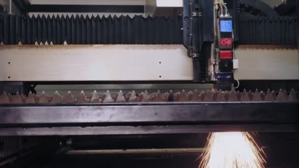 Machine de découpe laser pour tôle. Gros plan. vue latérale. machine moderne avec laser à fibre CNC coupe des motifs sur plaque de tôle. étincelles lumineuses volent du faisceau laser pendant la coupe — Video