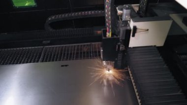 Metal levha için lazer kesme makinesi. Üst Manzara. CNC fiber lazerli modern makine metal levha üzerindeki desenleri kesiyor. Kesme işlemi sırasında lazer ışınından parlak kıvılcımlar uçuşuyor