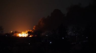 Yangın felaketi. Gece görüşü, korkunç turuncu alevler ve siyah dumanla yanan bina. Alevler içinde yanan bir ev. Şehirde yangın faciası.