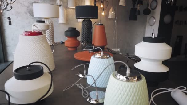 Lampen en kroonluchters in de winkel. assortiment verlichtingstoestellen voor interieur. half gedemonteerde keramische kroonluchters, lampen liggen op tafel. in de showroom. lichte interieur decoratie. — Stockvideo