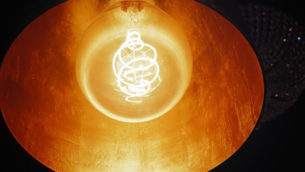 白熱灯だ。美しい螺旋状の電球は暖かい黄色の光で輝きます。金色のデザイナーシャンデリア。一番下だ。閉鎖. — ストック動画