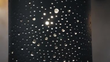 Avize. Yakın plan. Seramik gölgelik avizeler döner ve desenler boyunca sıcak ışık yayar. Güzel aydınlatma lambası..