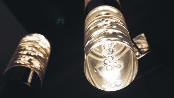 Ljuskronor i beredskap. närbild. vackra glas lysande lampa, med inredning i form av bubblor, hänger från taket i mörker. sortiment av belysningsarmaturer för inredning. — Stockvideo