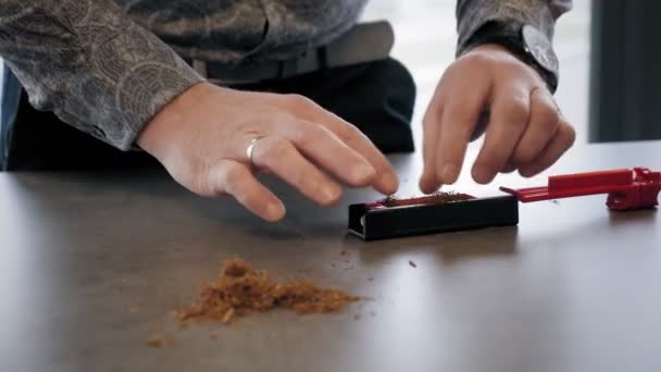 Tobak. Människan tar tobak på ett bord och sätter den i plast tobak rullande maskin, modern rökning pipa. Närbild. En man förbereder sitt tobaksrör — Stockvideo