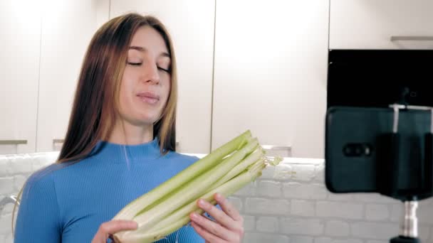 Mode de vie sain. nourriture saine. nutritionniste en ligne. belle femme tourne une vidéo avec smartphone dans la cuisine à la maison. elle se tient devant la caméra et parle d'une alimentation saine. Vlogging et social — Video