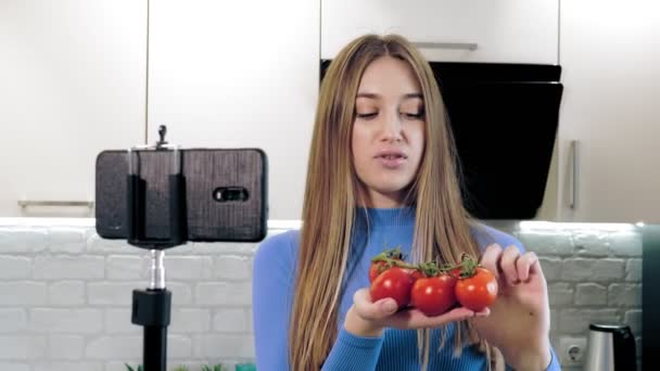 Mode de vie sain. nourriture saine. nutritionniste en ligne. belle femme tourne une vidéo avec smartphone dans la cuisine à la maison. elle se tient devant la caméra et parle d'une alimentation saine. Vlogging et social — Video